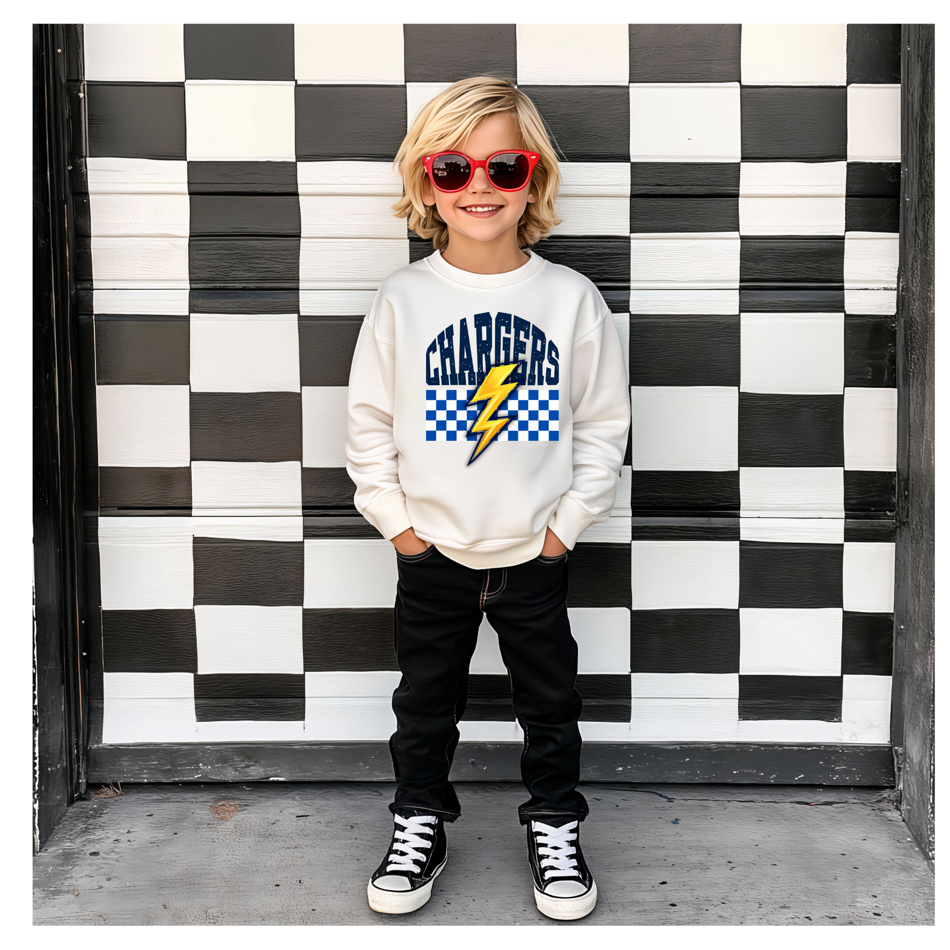 Child wearing a 'Chargers' sweatshirt with a checkered design in front of a black and white checkered wall.