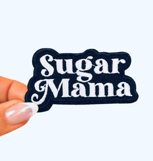 May include: A black fabric patch with white embroidered text that reads &#39;Sugar Mama&#39;.