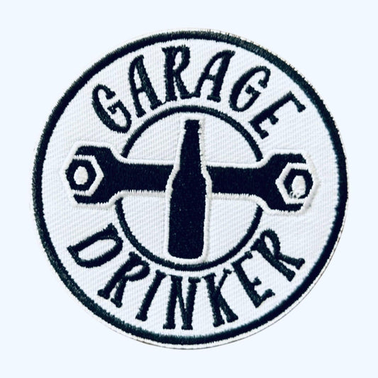May include: A white circular patch with black embroidered text and a wrench design. The text reads &#39;Garage Drinker&#39; with a bottle shape in the center.