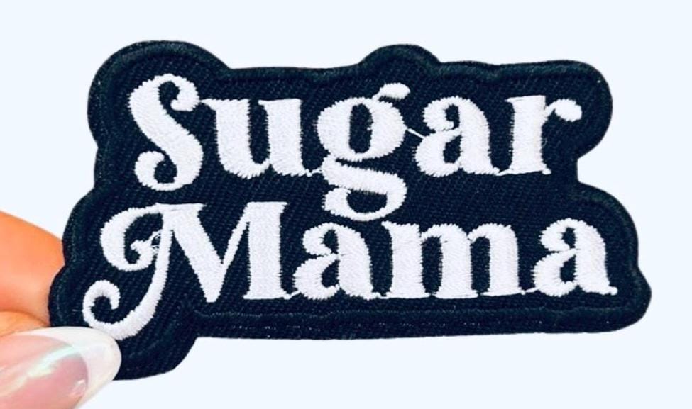 May include: A black fabric patch with white embroidered text that reads &#39;Sugar Mama&#39;.