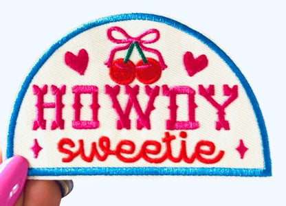 Pink, Red, and blue “howdy sweetie” iron on patch with red hearts and cherries with a pink bow. 4 inch half circle western patch.