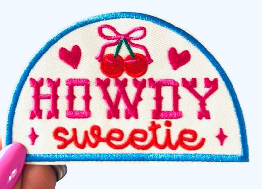Pink, Red, and blue “howdy sweetie” iron on patch with red hearts and cherries with a pink bow. 4 inch half circle western patch.