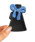 Black dress with blue bow patch held by a hand on a white background