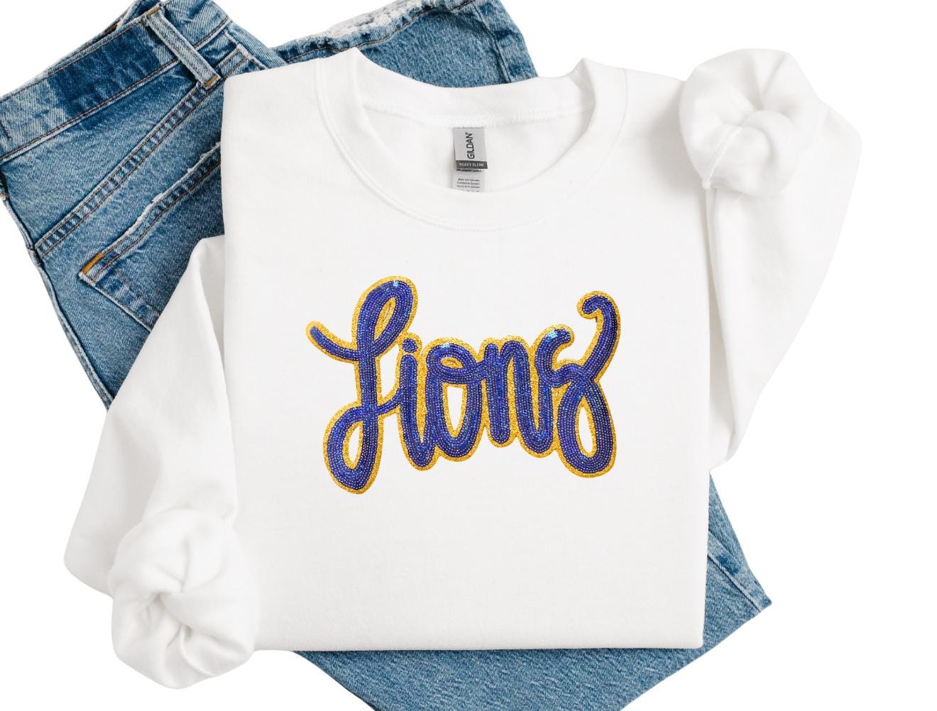 White sweatshirt with 'Lions' text on blue jeans